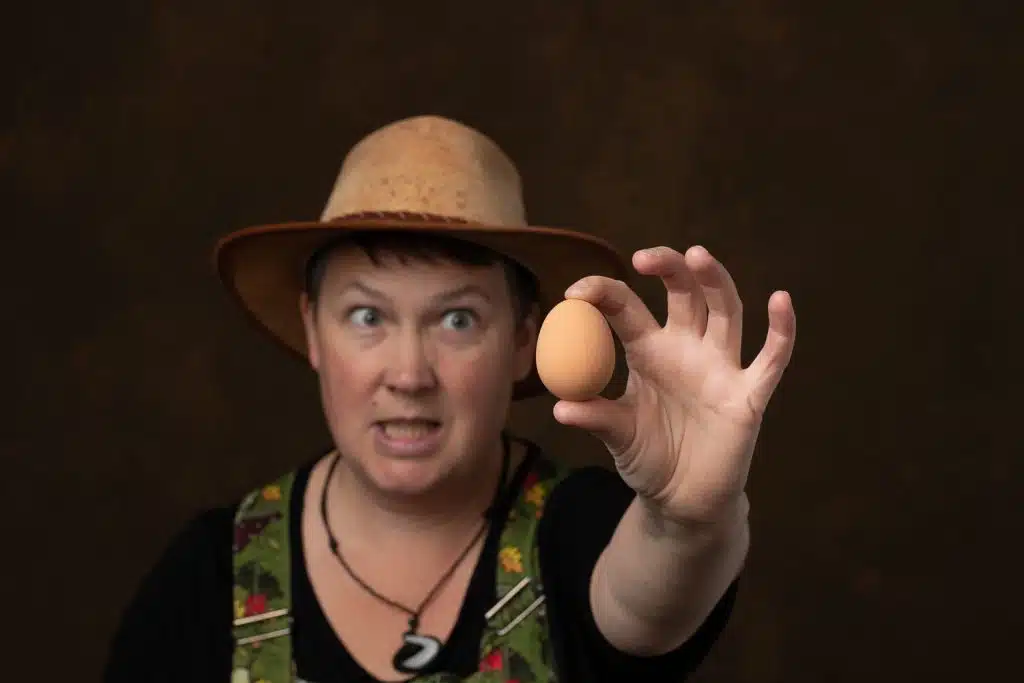 Storyteller Cara Roberts wearing a hat and holding an egg in one hand