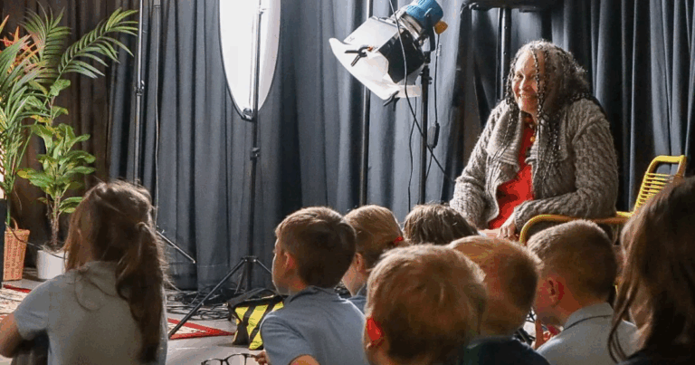 Start with Story - Sita Brand smiles over the heads of a group of schoolchildren watching a performance.