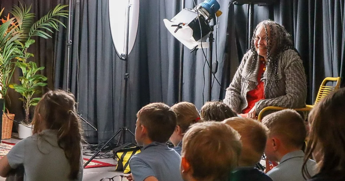 Start with Story - Sita Brand smiles over the heads of a group of schoolchildren watching a performance.
